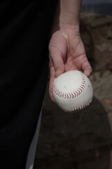 boy holding a baseball behind his back, back view, hands with a white ball