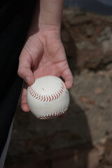 boy holding a baseball behind his back, back view, hands with a white ball.......