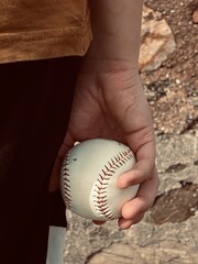 boy holding a baseball behind his back, back view, hands with a white ball
