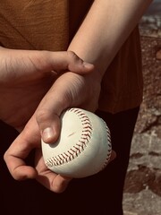 boy holding a baseball behind his back, back view, hands with a white ball