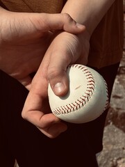 boy holding a baseball behind his back, back view, hands with a white ball