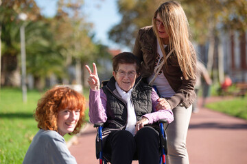 Elderly woman gesturing peace sign with caregivers in park