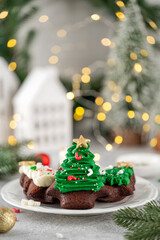 Christmas dessert. Chocolate Christmas tree brownies with butter cream and sugar sprinkles on top on a plate. Copy space.