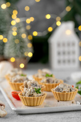 Christmas food. Mini tartlets with mushrooms in a cream sauce, with cheese, garlic and herbs on a ceramic board on a gray concrete background.