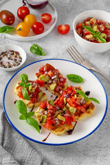 Grilled halloumi cheese with tomatoes, avocado, onion and balsamic sauce on a plate on a concrete background.