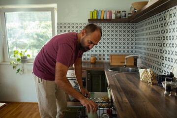 Man loading dishwasher in modern kitchen