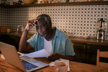 Senior black man looking stressed while using laptop at home