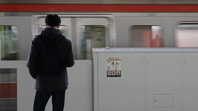 秋の朝の名古屋駅のホームで電車待ちの一人のサラリーマンの姿