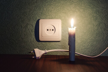 Power outage, candle with socket, power outage - no electricity, lit candle next to socket and plug...