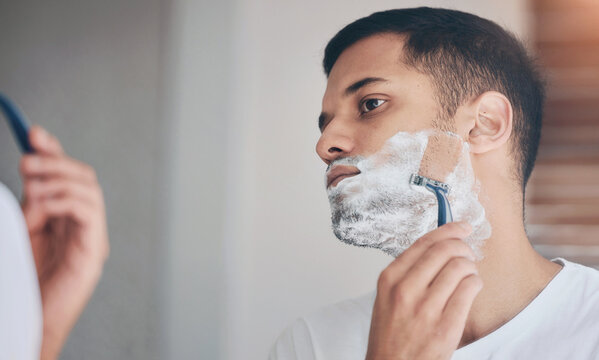 Shaving, mirror and man in bathroom with facial care, cleaning and getting ready in morning. Grooming, hair removal and male person in reflection with razor, foam on face and skincare routine at home