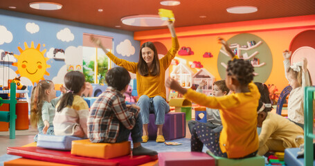 Cheerful Preschool Educator Playing, Singing and Dancing with Multiethnic Kids in Kindergarten....