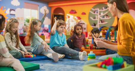 Happy Kindergarten Pedagogue Having a Conversation with Kids, Using Enthusiastic Teaching Methods in a Modern Colorful Kindergarten. Female Educator Stimulating Linguistic and Social Skills