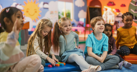 Cheerful Daycare Teacher Using Gaming and Acting Methods to Teach Multiethnic Kids Alphabet in Kindergarten. Small Cute Boys and Girls Getting Basic Reading and Writing Skills, Learning Alphabet