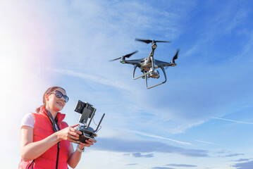 A young woman controls a drone with a remote control in her hands.