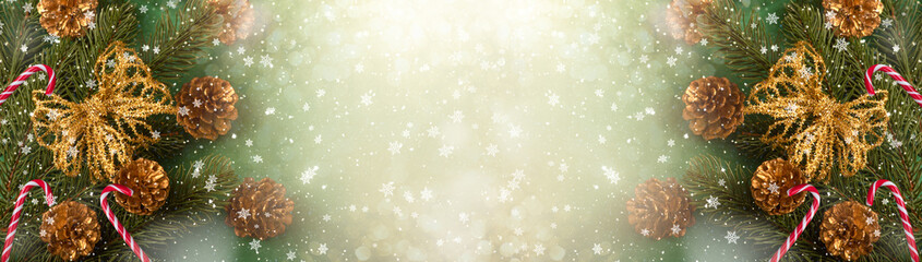 Christmas background with set of branch, golden bow, candy cane and cones for tree decoraton. New Year winter holidays concept in green and gold colors and copy space, top view wide panoramic banner.