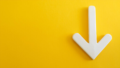 White wooden arrow pointing down on yellow background. Business, market decline or economic.