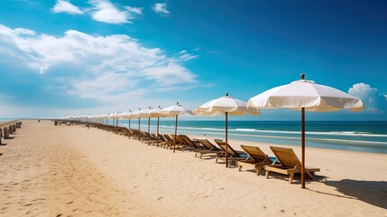 Fototapeta premium Sandy beach with rows of sun loungers and white umbrellas under a clear blue sky