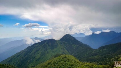 Fototapeta premium Scenic view of lush green mountains under a dramatic cloudy sky