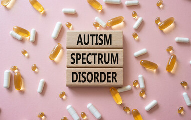 Autism Spectrum Disorder symbol. Concept word Autism Spectrum Disorder on wooden blocks. Beautiful pink background with pills. Medicine and Autism Spectrum Disorder concept. Copy space