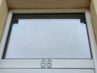  Number 66 on Glass Door Frame, Isolated in Negative Space with Sky Reflection