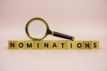 Magnifying glass and paper card with text NOMINATIONS on pink background