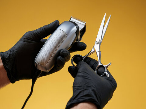 Primer plano de manos masculinas sosteniendo cortapelos y tijeras sobre fondo amarillo
