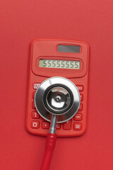 Red Calculator with Stethoscope on Red Background: Symbol of Financial Health Assessment