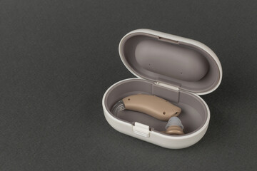 Modern Hearing Aid in Protective Case on Dark Background