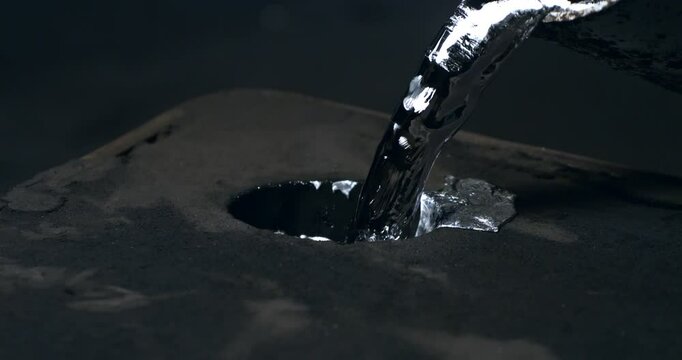 Super slow motion close up of aluminum metal foundry process in industrial factory, 1000 fps. Molten metal flows, splashes and hardens as it's poured into molds, showcasing precision and craftsmanship