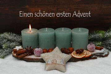 Dekoration zum ersten Advent: Adventskranz mit grünen Kerzen und dem Text einen schönen ersten Advent.