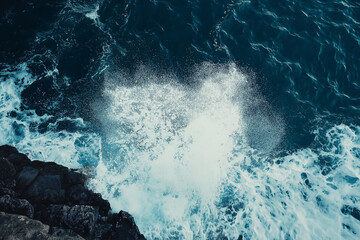Fototapeta premium Powerful ocean waves crashing against dark rocks, showing the raw energy and force of nature. Captivating seaside scene with dramatic effect.