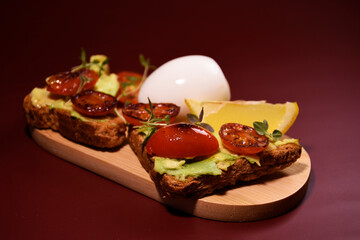Healthy breakfast. toast with avocado paste and fried tomatoes, boiled egg on a wooden board.