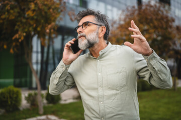 senior man talk on mobile phone while stand in front modern building