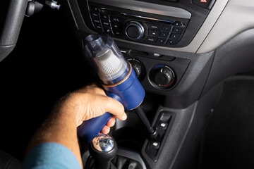 A person is cleaning the inside of a car with a vacuum