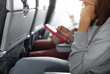 Person traveler on plane using smartphone 