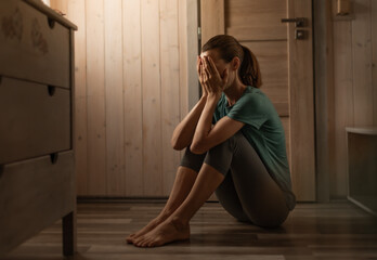 Sad tired unhappy woman sitting on the floor 