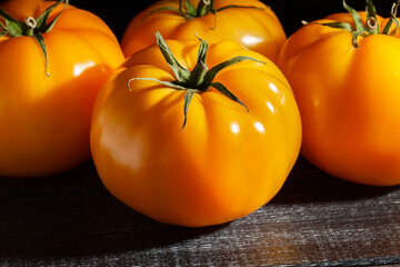 yellow tomato on black wood background