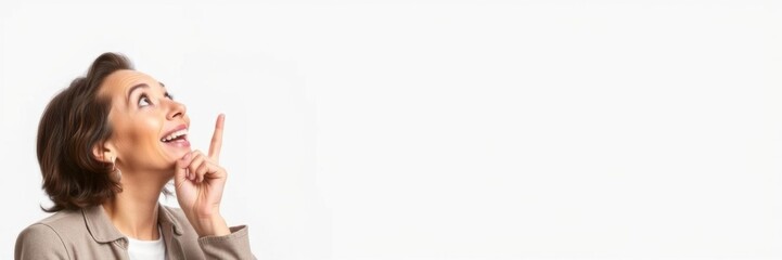 Fototapeta premium Excited middle-aged woman pointing upwards and to the side in surprise, with a big smile and wide eyes, emotion, amazed