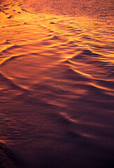 Golden sunset reflecting on the rippling water of sopot beach, poland, creating a mesmerizing and warm natural abstract pattern