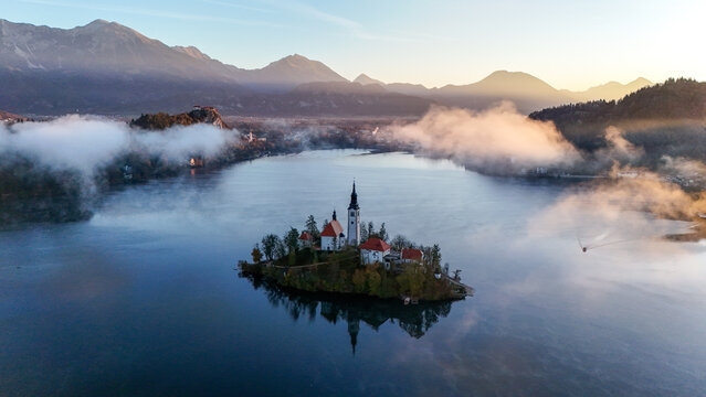 Bled lake in the morning. Aerial morning view of church of Assumption of Maria on Bled lake. Foggy autumn sunrise in Julian Alps, Slovenia, Europe.