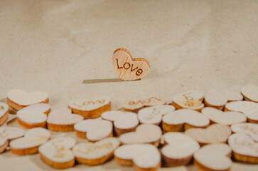 Wooden heart on kraft paper background with inscription love Copy space Wedding invitation card Valentine Birthday Defocused bokeh effect Front view