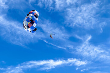 a colorful parachute flies in the vast blue sky.