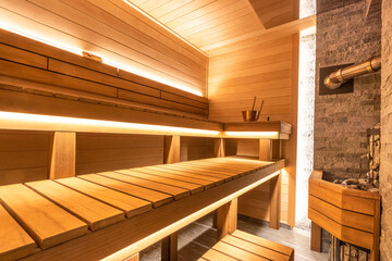 Sauna with traditional accessories. The heating element is at the brick wall. Healthy lifestyle and spa treatments.