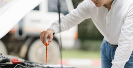 Checking the Oil:  A close-up shot of a man checking the oil level in his car engine, showcasing...
