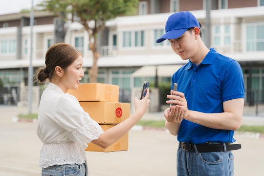Delivery Confirmation: A smiling woman receives a package from a delivery driver, confirming the delivery on her phone. The image captures the convenience and reliability of modern delivery services.