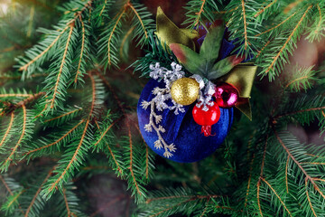 Luxurious blue color handmade Christmas toy against a background of Christmas tree branches