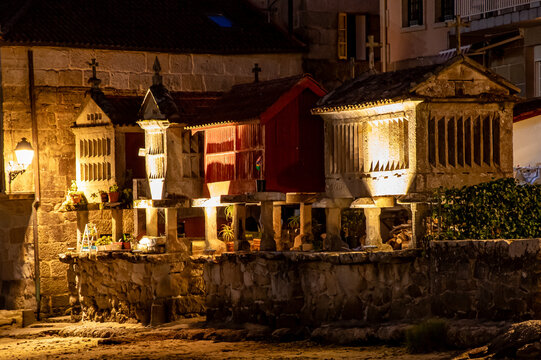four horreos by the sea lit up at night in combarro, galicia