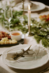 Vertical shot of porcelain plate with cotton napkin in stick shaped napkin ring on decorated table for X-mas eve