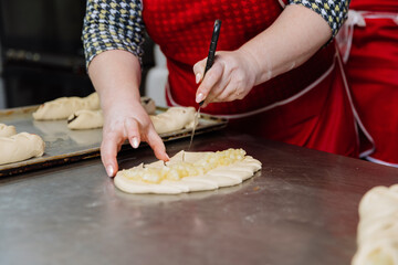 Hands skillfully scoring dough filled with apple topping, preparing for baking perfection