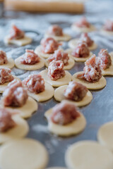 Raw dumplings in progress, freshly prepared dough circles topped with seasoned meat filling